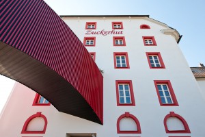 Außenaufnahme des gebäudes Zuckerhut mit weißer Fassade und roten Fenstern von Architekt Kuchenreuther