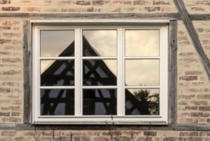 Spiegelung eines Fachwerkhauses in Fenster mit Holzrahmen