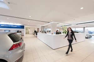 Weitwinkel-Aufnahme in Autohaus mit Blick auf Mitarbeiter und Automobile. Feigfotodesign