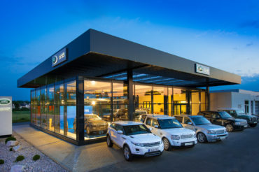 Außenaufnahme Gebäude Autohaus Landrover mit PKWs bei Dämmerung. Feigfotodesign