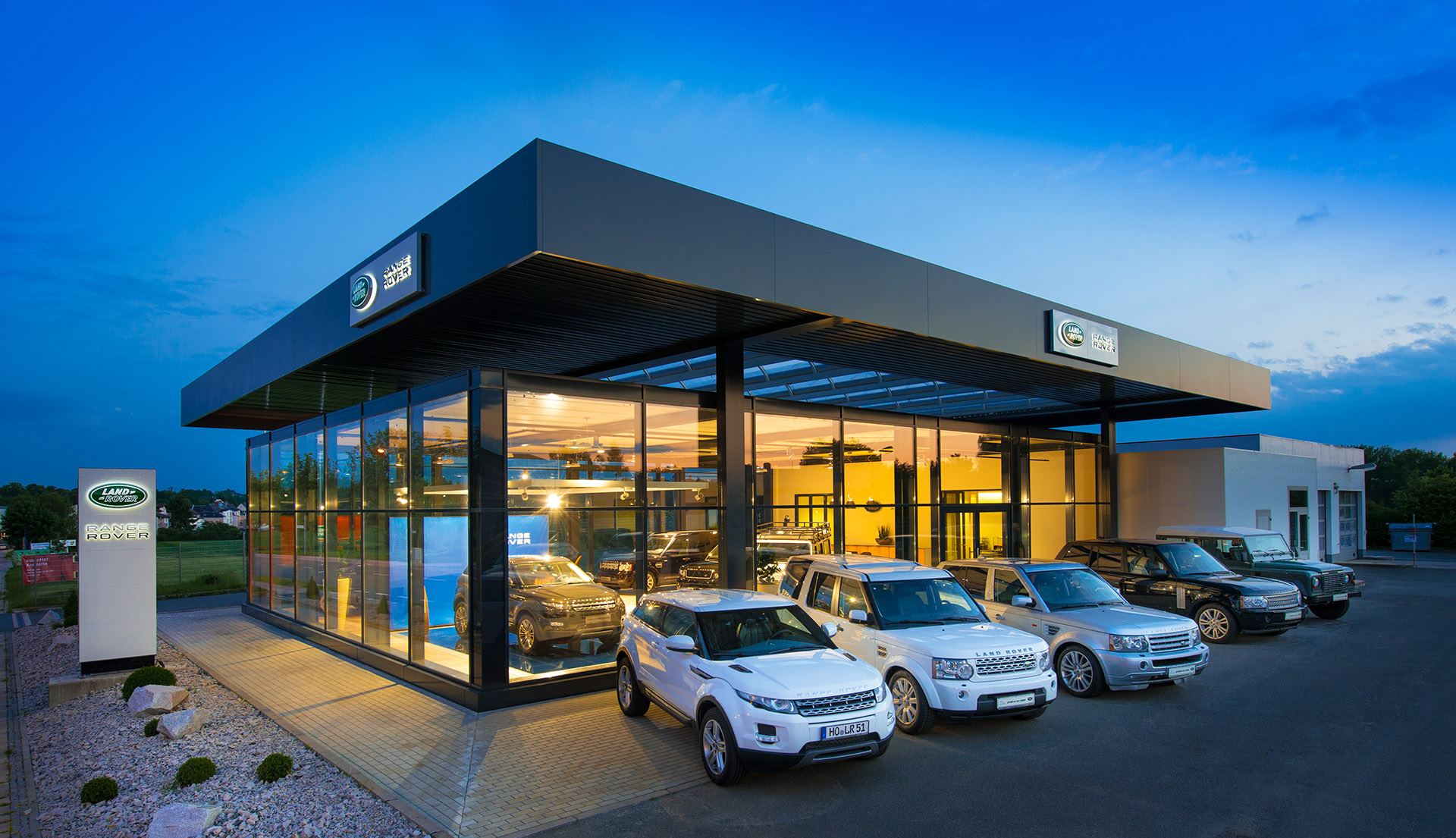 Außenaufnahme Gebäude Autohaus Landrover mit PKWs bei Dämmerung. Feigfotodesign