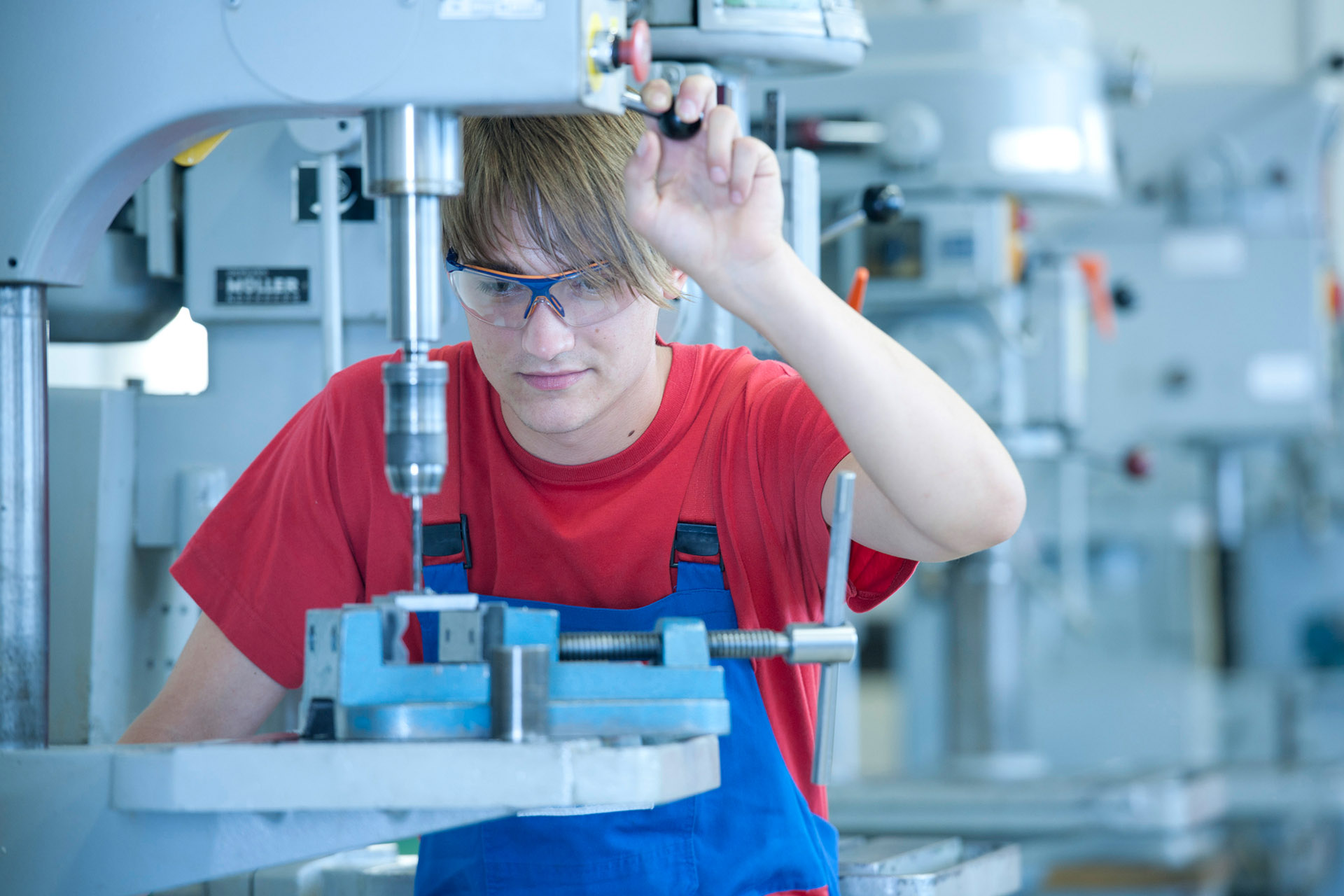 Industriefotografie Mitarbeiter mit Schutzbrille bohrt. Feigfotodesign