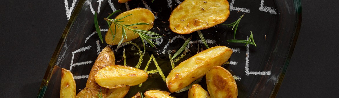 Werbefotografie Gebackene Kartoffelspalten mit Rosmarin und Salz in Auflaufform