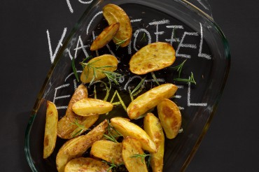 Werbefotografie Gebackene Kartoffelspalten mit Rosmarin und Salz in Auflaufform