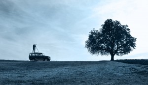 Land-Rover Defender in Natur mit Fotograf und Stativ auf Dach. Feigefotodesign