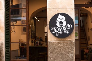 Schwarz weißes Logo an Steinfassade vor kleiner Bar in Tramuntana. Feigefotodesign