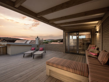 Außenaufnahme Ferienwohnung Alte Schreinerei auf Sonnenterrasse neben Saunabereich mit Blick auf Hohenberg in Dämmerung. Feigefotodesign